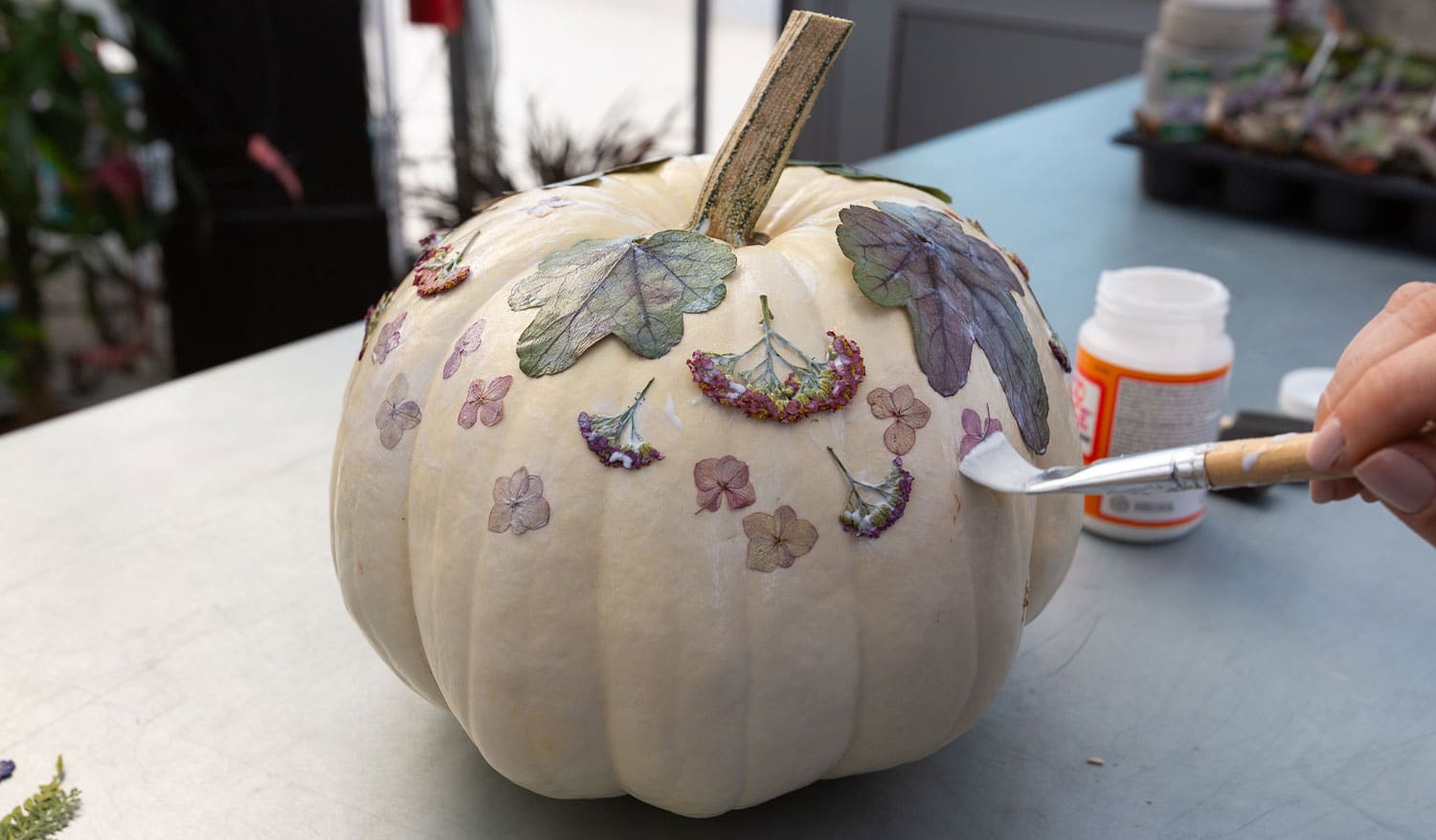 Lily adding more dried flowers to the pumpkin