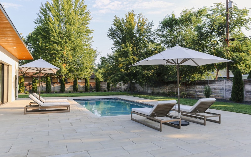 Photo of landscape design with pool, paver patio, seating, and umbrellas
